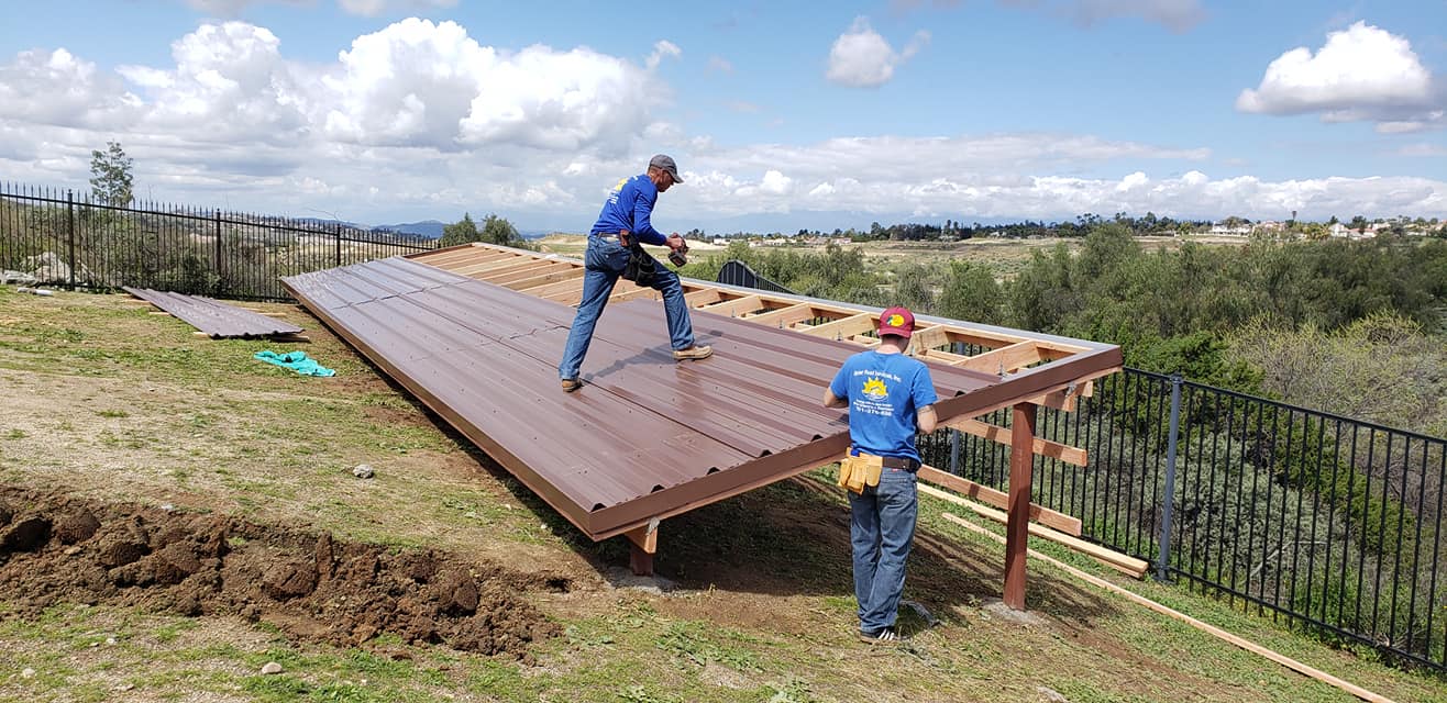 Crew members building a raised solar mounting rack on a hillside lot above the valley